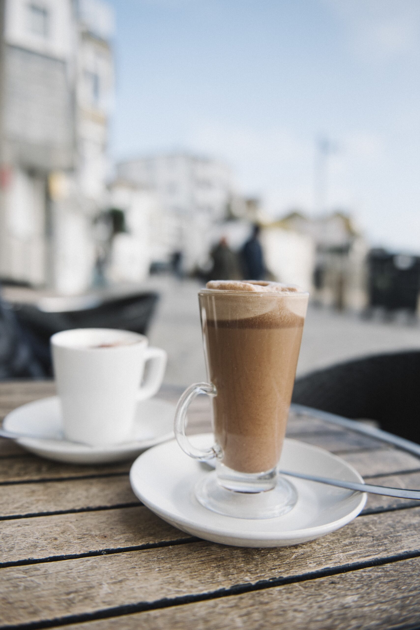 A vertical shot of a cup of cold coffee on the table with a blurred background